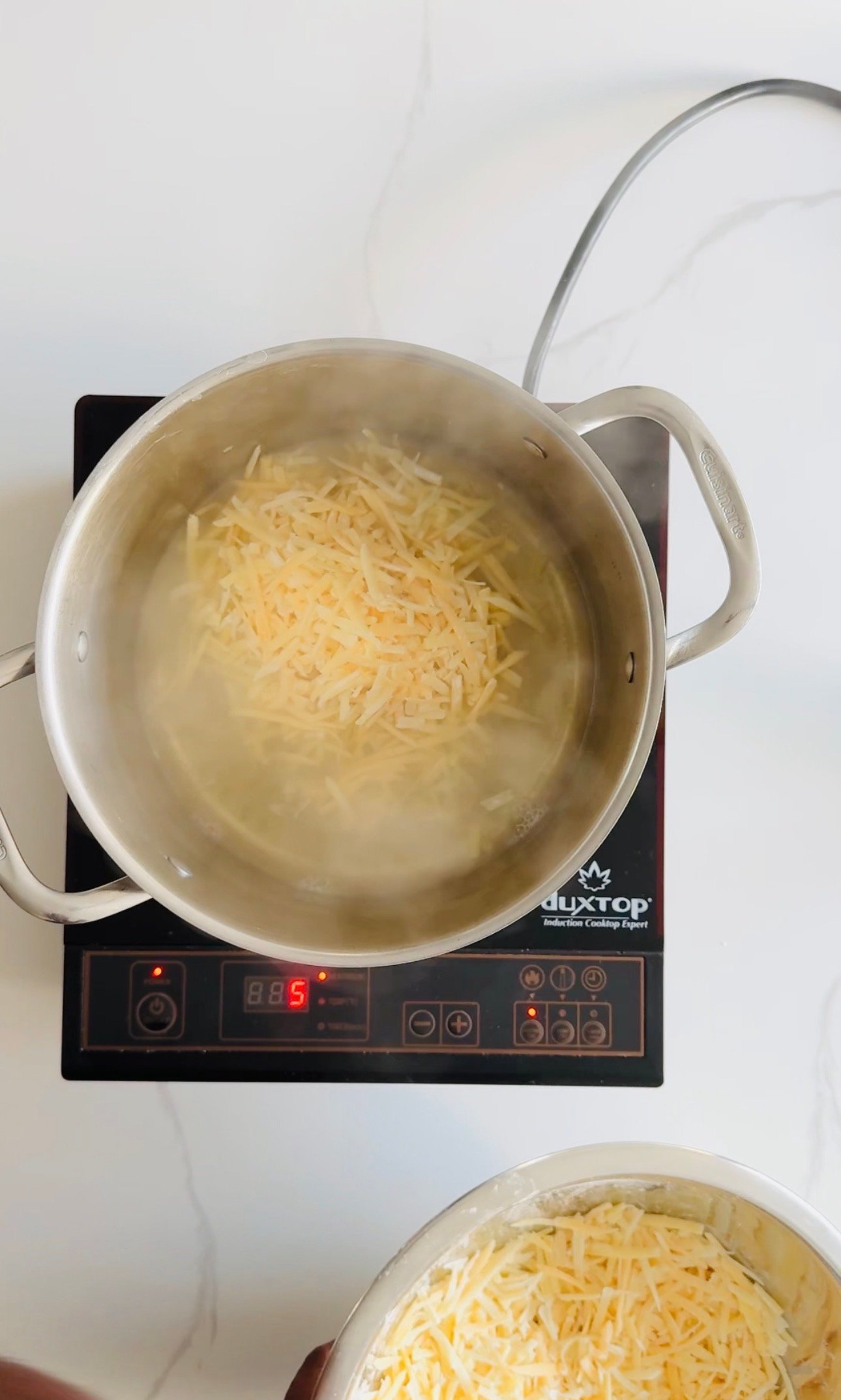 Grated cheeses melting together in a saucepan as the Swiss-inspired fondue is prepared.