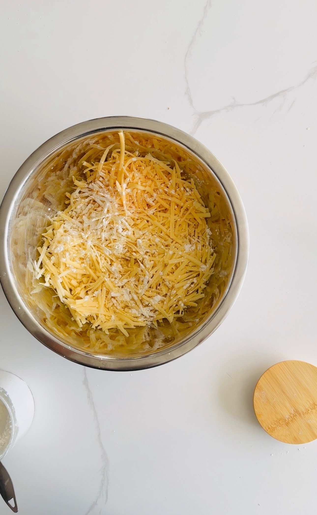 Freshly grated Gruyère and Gouda cheese being prepared with cornstarch before melting into fondue.